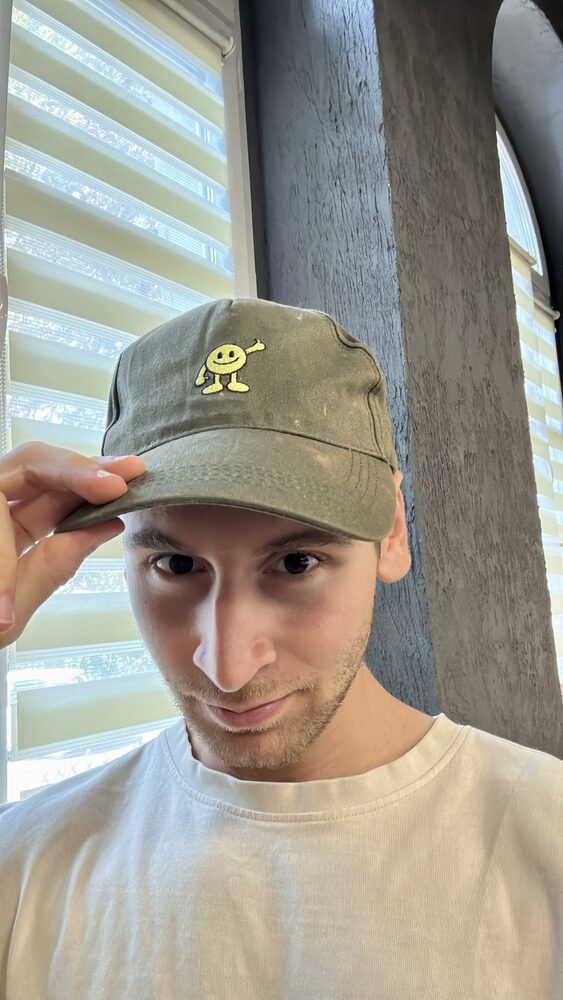 A worn cap with a smiling figure on it